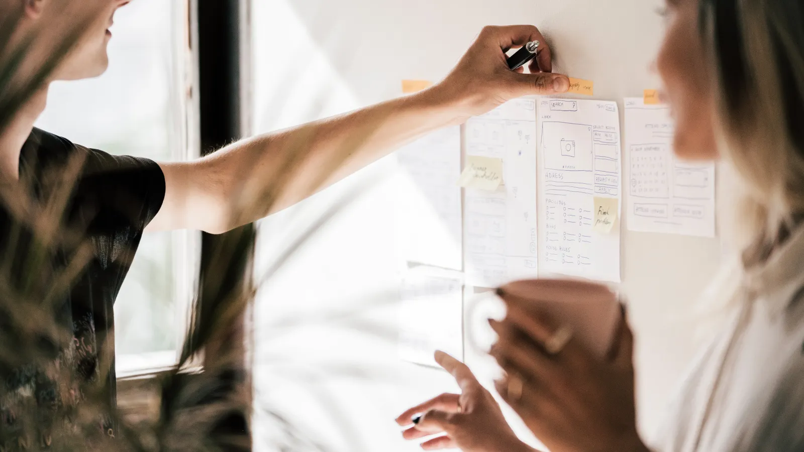Two people talking and putting a paper on a wall