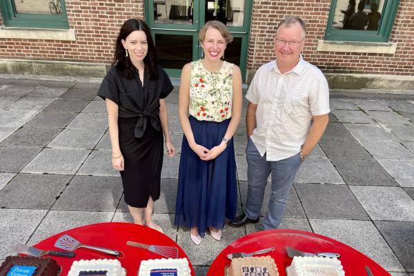 3 adults posing in front of cakes with book titles on the cakes