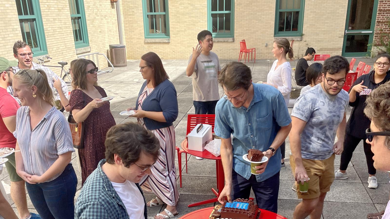 Students and faculty eating cakes outside 