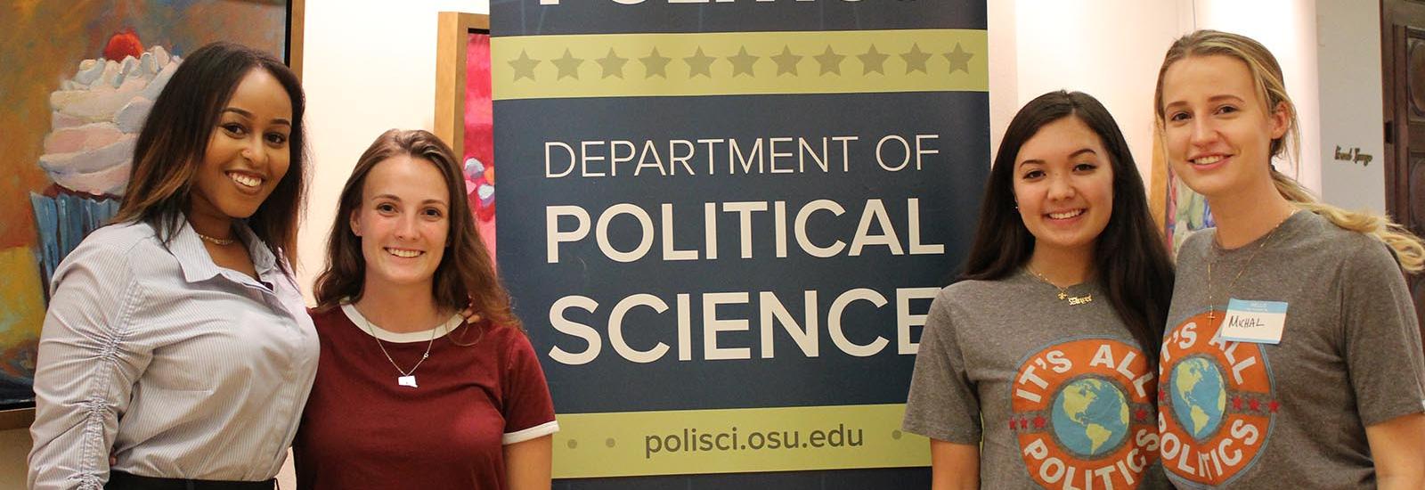 Students standing in front of a department banner